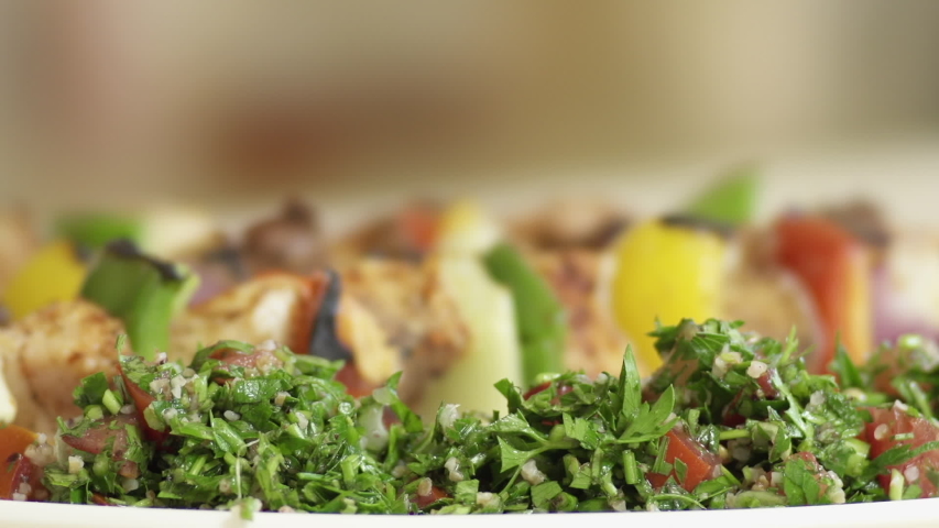 Pouring pomegranate molasses on Tabbouleh Salad. Mediterranean cuisine. Roasted meat skewers in the background Royalty-Free Stock Footage #1056181325