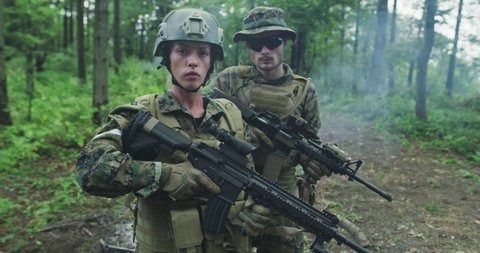 Portrait of team with male and female soldiers in dense forest with smoke in background