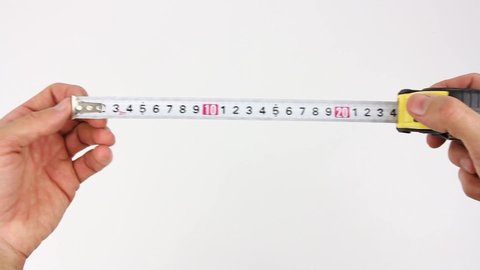 human hands slowly pull the measuring tape out of tape measure and measure the length or width or dimensions, then release the tape and it fast drives back in, close up view on white background