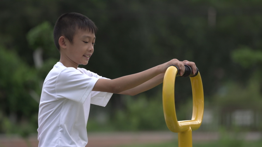 Kids playing and exercing on public outdoor gym park, boy children holding equipment and smile to enjoy play and exercise for good health for outside reaction on blurred background, Asian kids child
