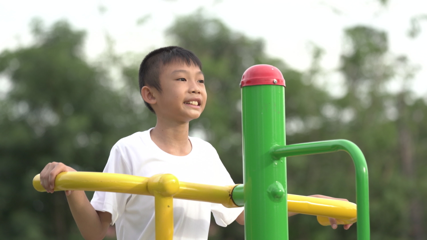 Kids playing and exercing on public outdoor gym park, boy children holding equipment and smile to enjoy play and exercise for good health for outside reaction on blurred background, Asian kids child