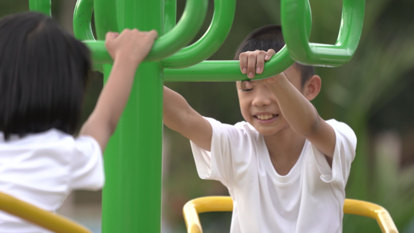 Kids playing and exercing on public outdoor gym park, boy girl children holding equipment and smile enjoy play and exercise for good health for outside reaction on blurred background, Asian kids child