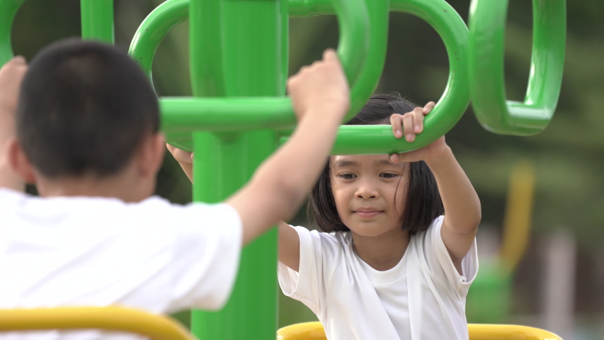 Kids playing and exercing on public outdoor gym park, boy girl children holding equipment and smile enjoy play and exercise for good health for outside reaction on blurred background, Asian kids child