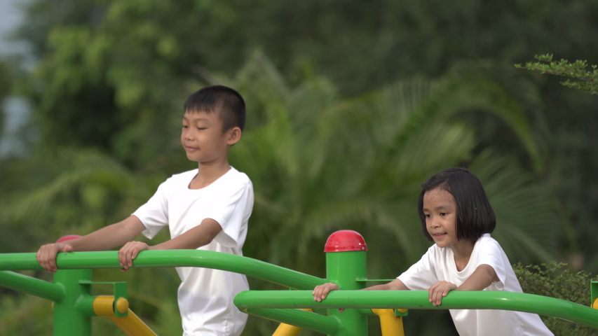 Kids playing and exercing on public outdoor gym park, boy girl children holding equipment and smile enjoy play and exercise for good health for outside reaction on blurred background, Asian kids child