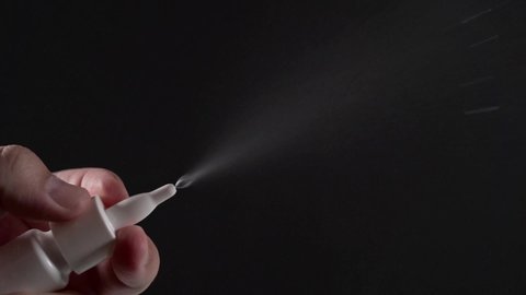 Nasal Spray in white bottle at black background, Liquid Water Spray against allergy, influenza or another virus, slow motion