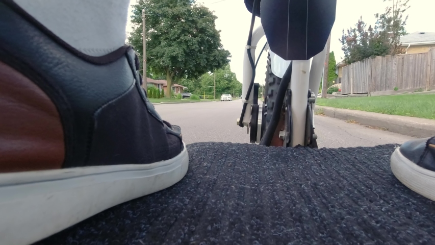 Riding scooter POV through the house area of the city. Motor wheel, driver legs and asphalt road. Recreational leisure. Driving ecological environmentally conscious power transport. Active lifestyle.