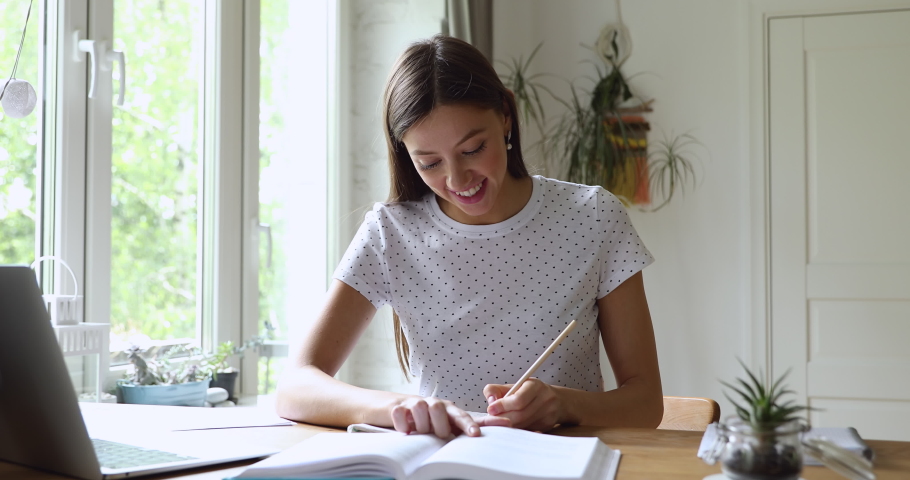 Student girl sitting at desk holds pencil writing essay read textbook, do homework enjoy easy interesting learning process, self-education activity, higher education, gain knowledge, brainwork concept Royalty-Free Stock Footage #1056190217