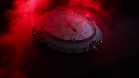 Time concept. Big vintage round clock on wooden table with abstract light. Dark atmosphere. Creative decoration. Selective focus
