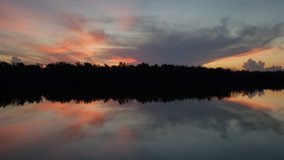 Sounds and sights of sunrise on West Lake in Everglades National Park, Florida on tranquil summer morning with colorful cloudscape reflected in calm water 4K.