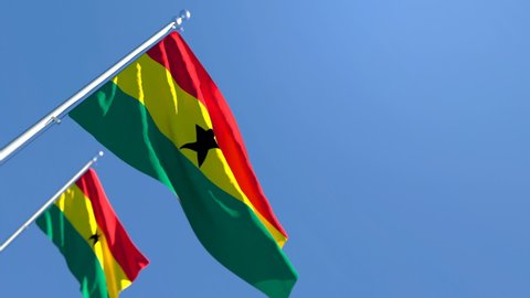 The national flag of Ghana is flying in the wind against a blue sky