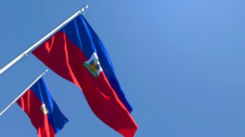 The national flag of Haiti is flying in the wind against a blue sky
