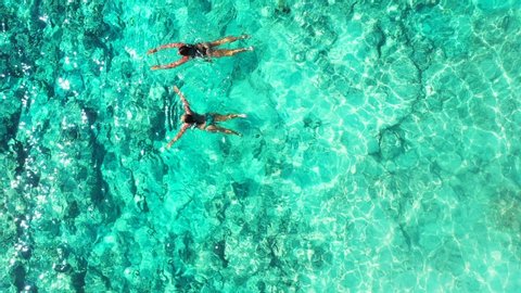 Seychelles. Attractive women swimming in the beautiful clear turquoise sea. Aerial