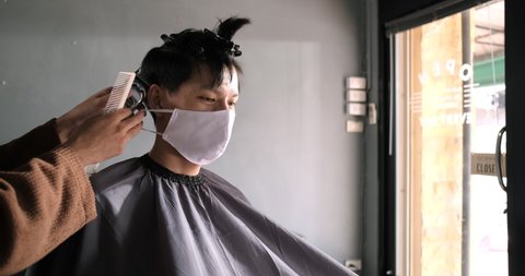 Asia Barber Shop Hair cut queueing customer's wearing face mask prevention business reopening after coronavirus lockdown, Men's hairstyling and new normal lifestyle concept.: film stockowy