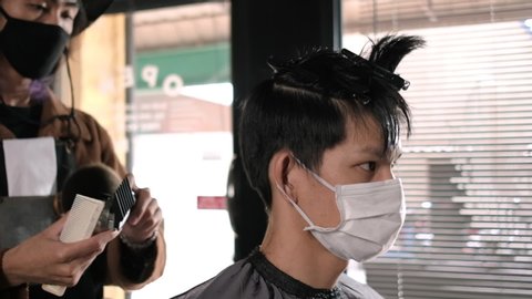 Side view Close up Slow motion: Barber Shop Hair cutting queueing customer's wearing face mask prevention business reopening after coronavirus lockdown, Men's hairstyling and new normal lifestyle.