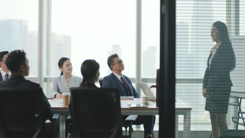 young asian business woman speaking during team meeting in conference room of modern corporation