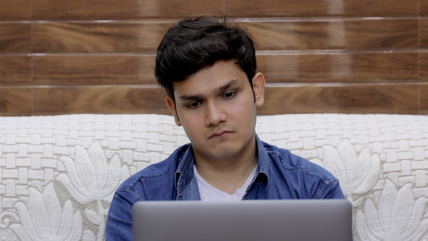 A young college student is disappointed after seeing his semester results on his laptop. Handsome Indian guy is depressed after looking at his exam result on his digital laptop - expressions concept Royalty-Free Stock Footage #1056200759