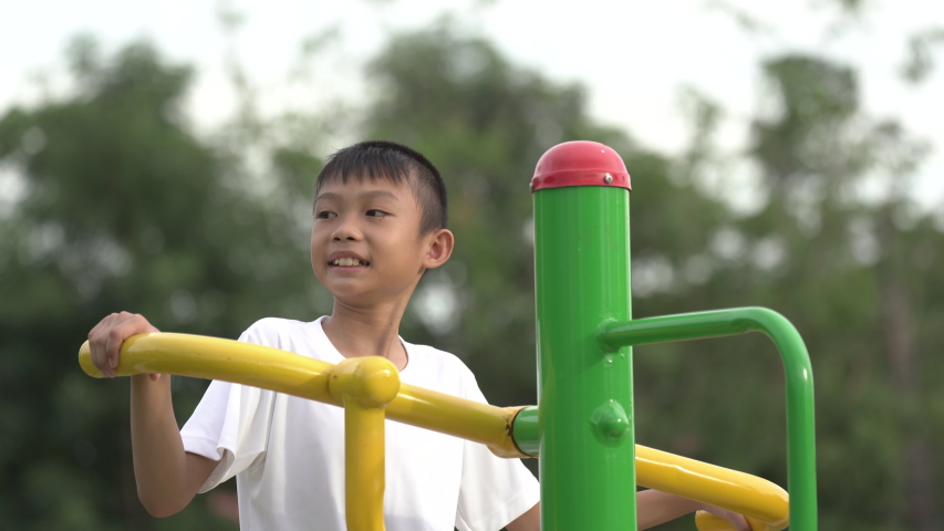 Kids playing and exercing on public outdoor gym park, boy children holding equipment and smile to enjoy play and exercise for good health for outside reaction on blurred background, Asian kids child