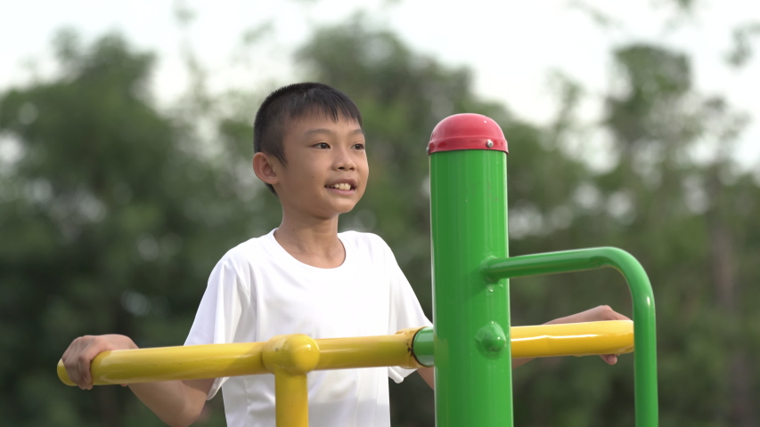 Kids playing and exercing on public outdoor gym park, boy children holding equipment and smile to enjoy play and exercise for good health for outside reaction on blurred background, Asian kids child
