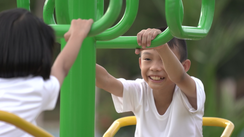 Kids playing and exercing on public outdoor gym park, boy girl children holding equipment and smile enjoy play and exercise for good health for outside reaction on blurred background, Asian kids child