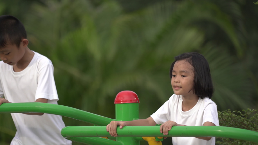 Kids playing and exercing on public outdoor gym park, boy girl children holding equipment and smile enjoy play and exercise for good health for outside reaction on blurred background, Asian kids child