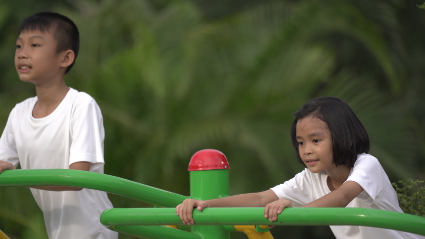 Kids playing and exercing on public outdoor gym park, boy girl children holding equipment and smile enjoy play and exercise for good health for outside reaction on blurred background, Asian kids child