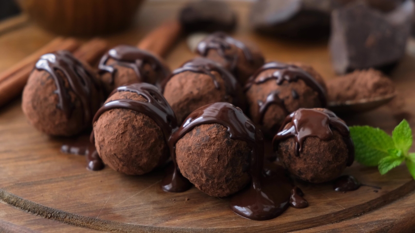 Glazed chocolate truffles on wooden background. Pouring chocolate glaze on chocolate truffles. Domestic confectionery Royalty-Free Stock Footage #1056200945