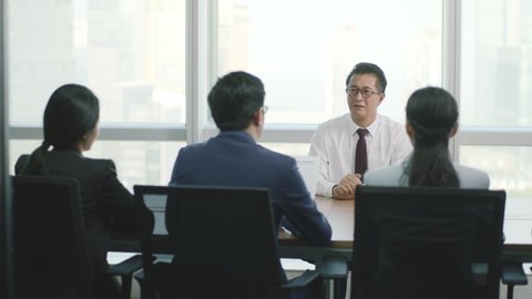 nervous mature asian business man being interviewed by a group of HR executives in office of modern company