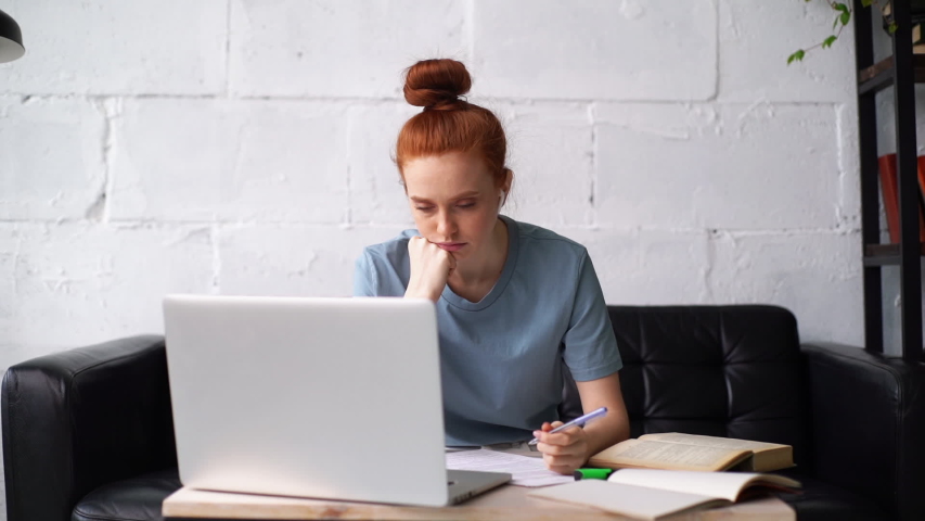 Bored lazy redhead young businesswoman is working on laptop computer and with paper documents. Tired business lady sleeping above documents. Focused girl student distance learning at home office. | Shutterstock HD Video #1056207365