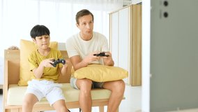 Father and son using joystick controller for playing games in bedroom.