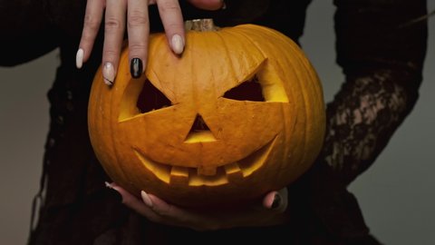 Стоковое видео: Young witch holding pumpkin on halloween. Halloween. concept. Close-up of hands in 4K, UHD