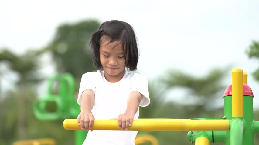Kids playing and exercing on public outdoor gym park, girl children holding equipment and smile to enjoy play and exercise for good health for outside reaction on blurred background, Asian kids child