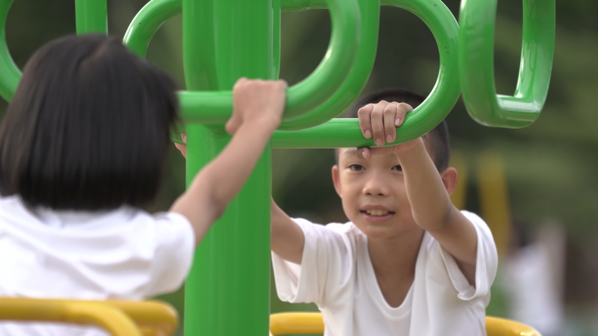 Kids playing and exercing on public outdoor gym park, boy girl children holding equipment and smile enjoy play and exercise for good health for outside reaction on blurred background, Asian kids child
