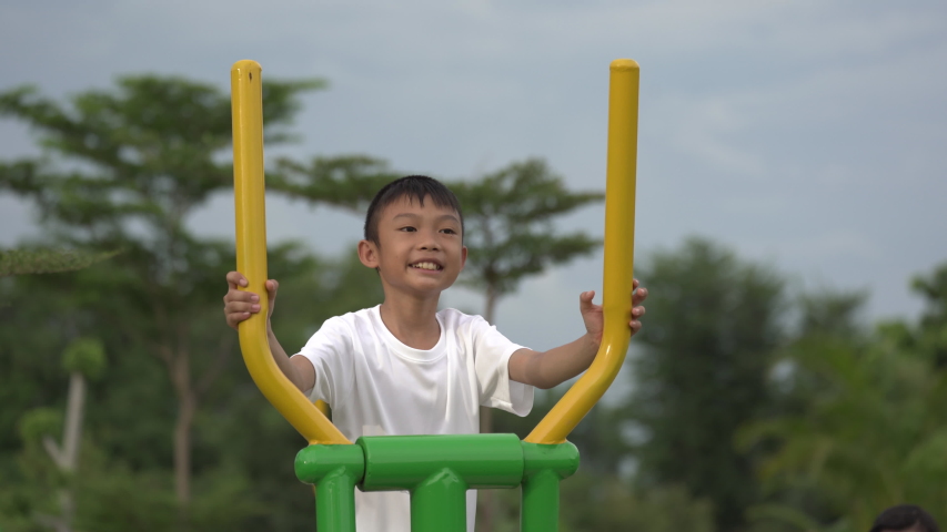 Kids playing and exercing on public outdoor gym park, boy children holding equipment and smile to enjoy play and exercise for good health for outside reaction on blurred background, Asian kids child