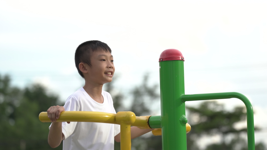 Kids playing and exercing on public outdoor gym park, boy children holding equipment and smile to enjoy play and exercise for good health for outside reaction on blurred background, Asian kids child
