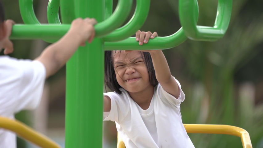 Kids playing and exercing on public outdoor gym park, boy girl children holding equipment and smile enjoy play and exercise for good health for outside reaction on blurred background, Asian kids child
