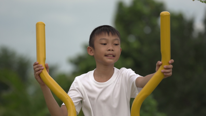 Kids playing and exercing on public outdoor gym park, boy children holding equipment and smile to enjoy play and exercise for good health for outside reaction on blurred background, Asian kids child