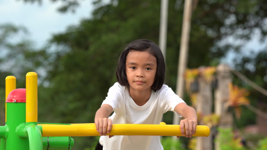 Kids playing and exercing on public outdoor gym park, girl children holding equipment and smile to enjoy play and exercise for good health for outside reaction on blurred background, Asian kids child