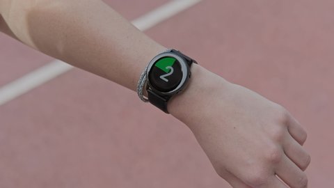 Runner starting smart watch timer and running. Smart watch on female wrist. Girl check pulse on fitness bracelet. Close-up in 4K, UHD