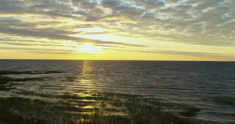 Lake, sunrise. The camera moves back slowly revealing the sun