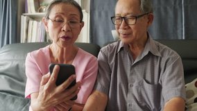 Asian old woman and old man hold mobile phone or tablet for talking and smiling on video call with son, daughter and grandchildren at home. Grandparents feel happy with communicate via internet. 
