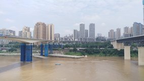 Landscape clip of train rails over a river with a train passing with the city of Chongqing , China in the background.