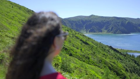 Young Woman looking to the landscape nature of the Fire Lagoon (Lagoa do Fogo) background enjoying vacation travel adventure in the Island of São Miguel in the Azores. 4K Footage.