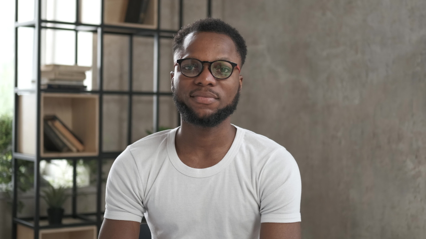 Happy student having online video chat conference looking at camera. Webcam view. Working from home office during the pandemic. Online education training. Portrait african american man in glasses Royalty-Free Stock Footage #1056237068