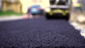 Vibratory asphalt paving machine on the sidewalk filmed close-up.Road works,pavement repair,hard work.Video clip