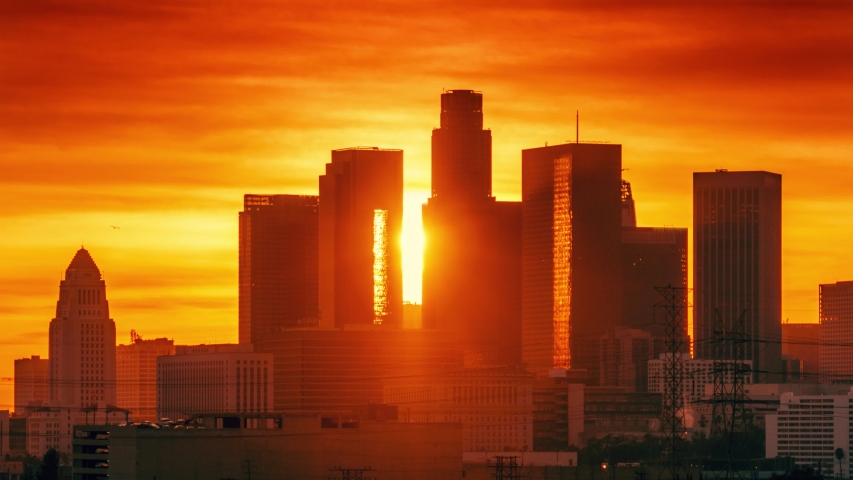 Sunset sun setting behind downtown Los Angeles skyline silhouette. Zoom in on landmark city buildings. Timelapse, 4K UHD.