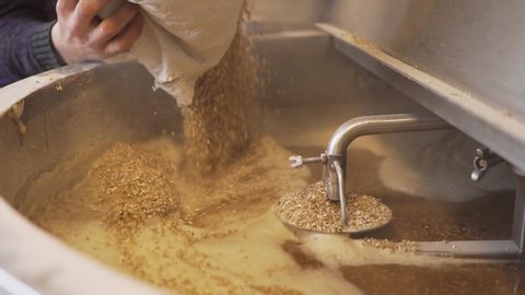 Beer Production - Pouring Malt Grains Into The Large Milling Tank In The Brewery - close up slowmo
