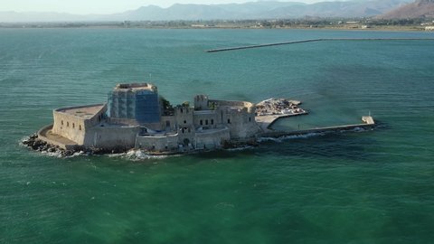 Aerial drone video of medieval Venetian small islet and fortress of Bourtzi built in bay of historic seaside town of Nafplio used as a prison in past times, Argolida, Peloponnese, Greece