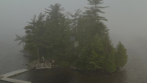 Thick fog surround island on Moosehead lake orbiting aerial