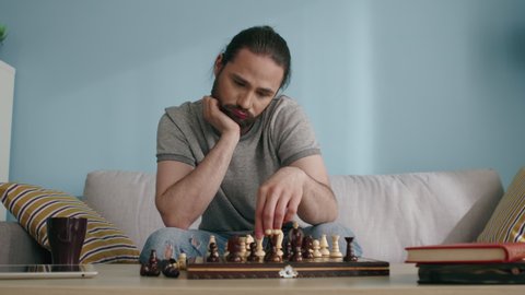 Sad lonely man plays chess alone, trying to kill time in isolation, tired and bored, misses his close people and friends, needs live communication, Slow motion.