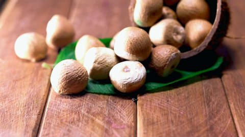 Areca nuts in wooden spoon with small green leaves,betel Nut or Areca Nut background,betel leaf edible eating culture of Asia,areca nuts in glass bowl on wooden,
